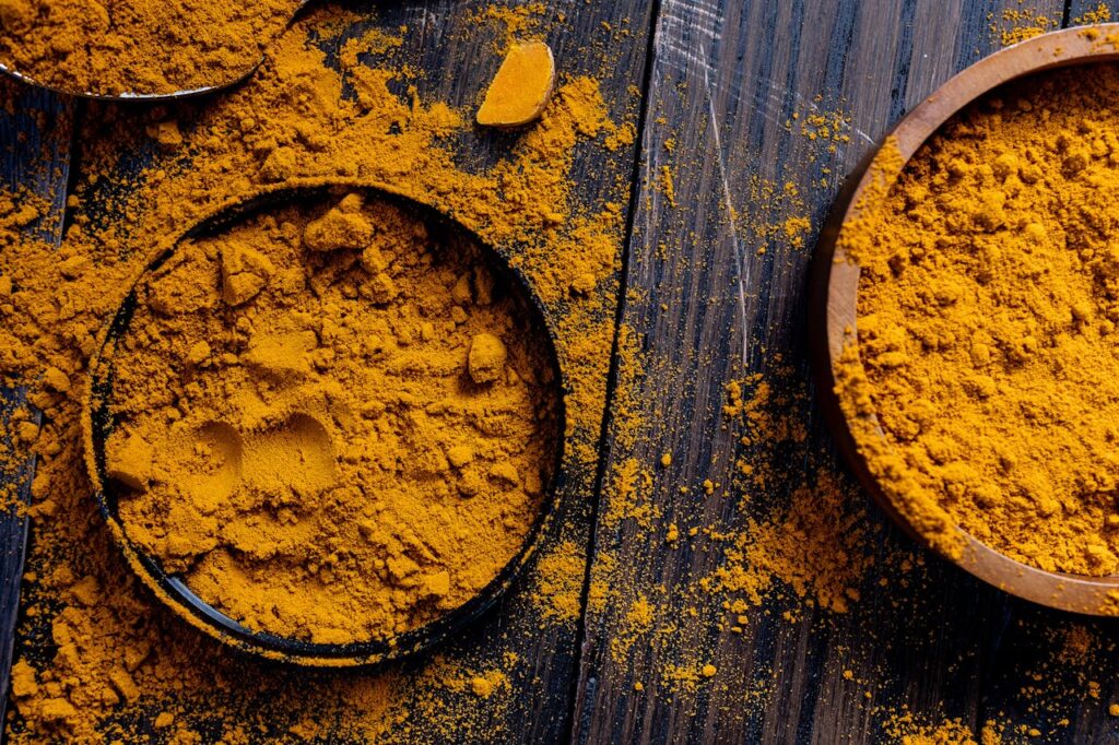Close-up of turmeric powder in rustic bowls on a wooden surface, ideal for spice and food photography.